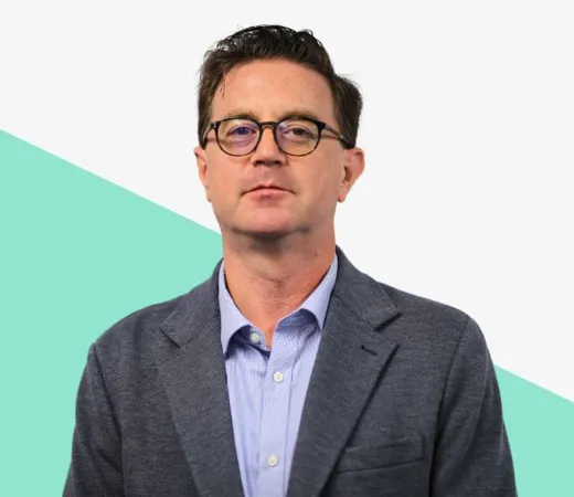 Man in glasses wearing a blazer, neutral background