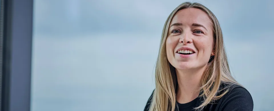 woman sitting at table with notepad and pen, smiling