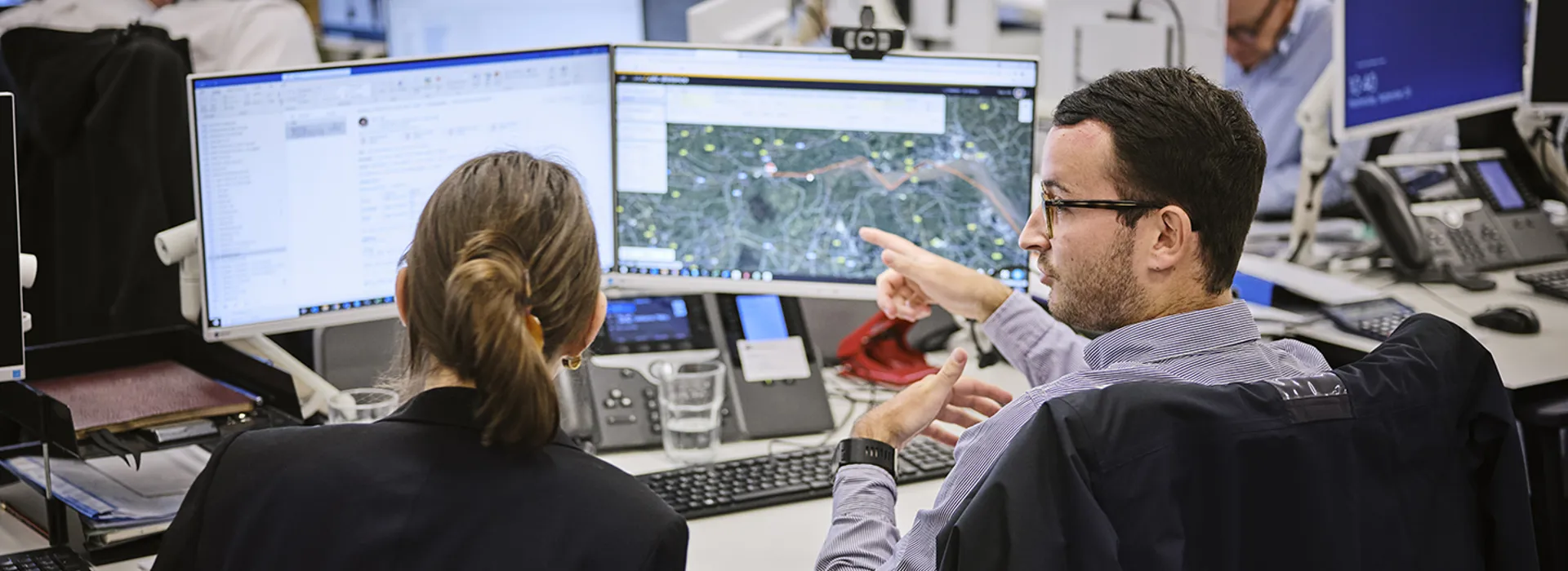 man at his desk explaining something on the screen to a female colleague