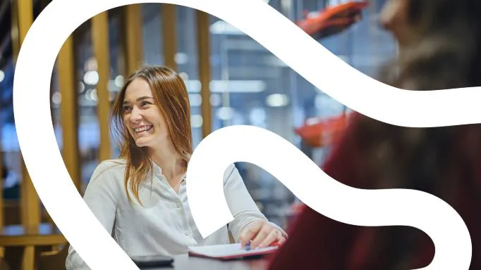 Smiling woman at a table with a notepad.