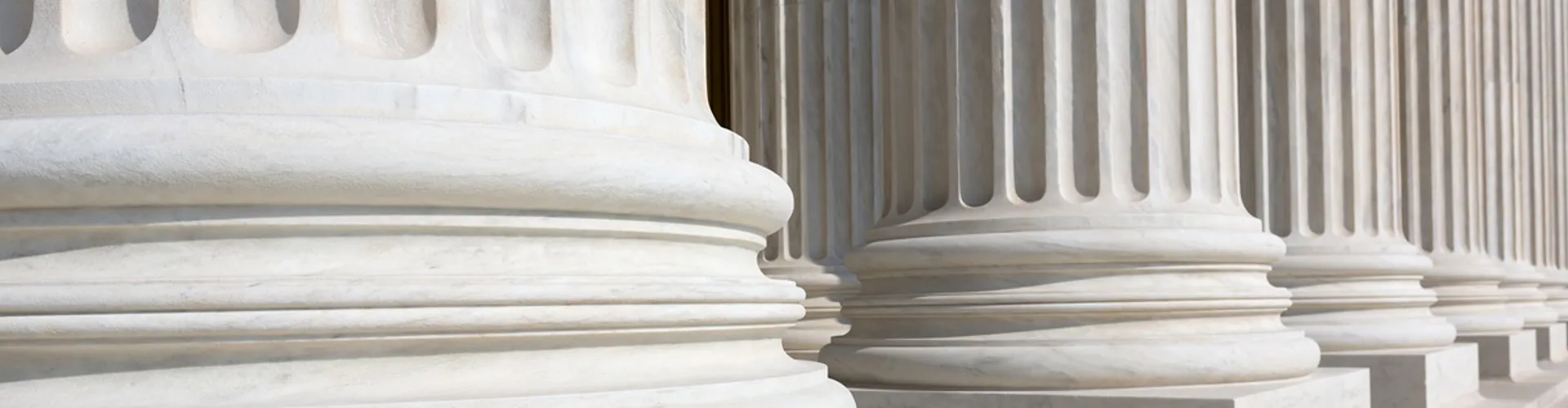 Close-up of several classical white marble columns with fluted designs.