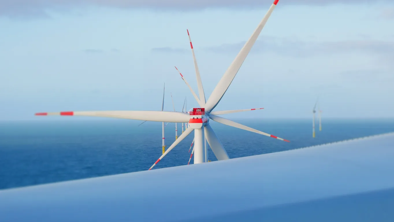 Close-up of a wind turbine with white blades and red markings against the ocean and sky.