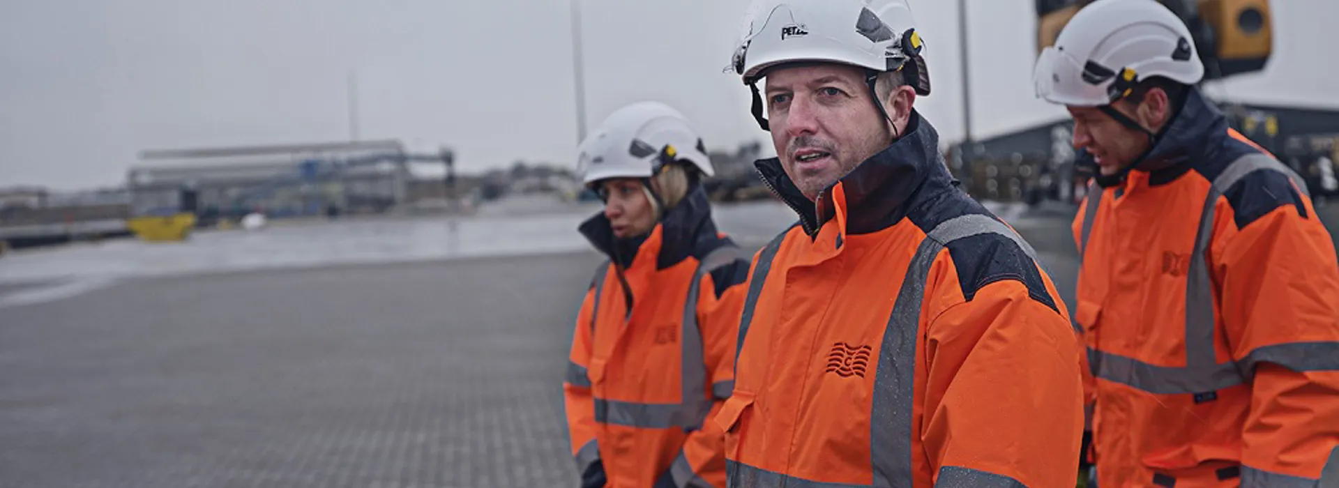 Three workers in uniform and helmets walking