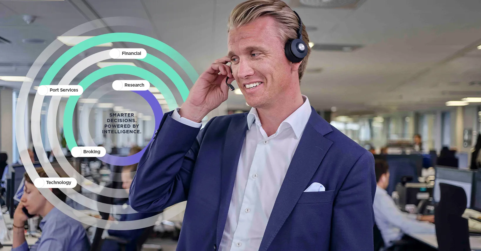 Smiling man in a dark suit and headset talking on the phone in an office, surrounded by text bubbles.