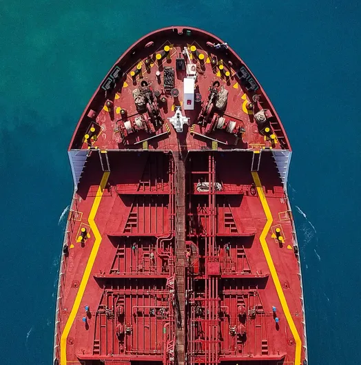 Top view of a large red cargo ship on blue water.