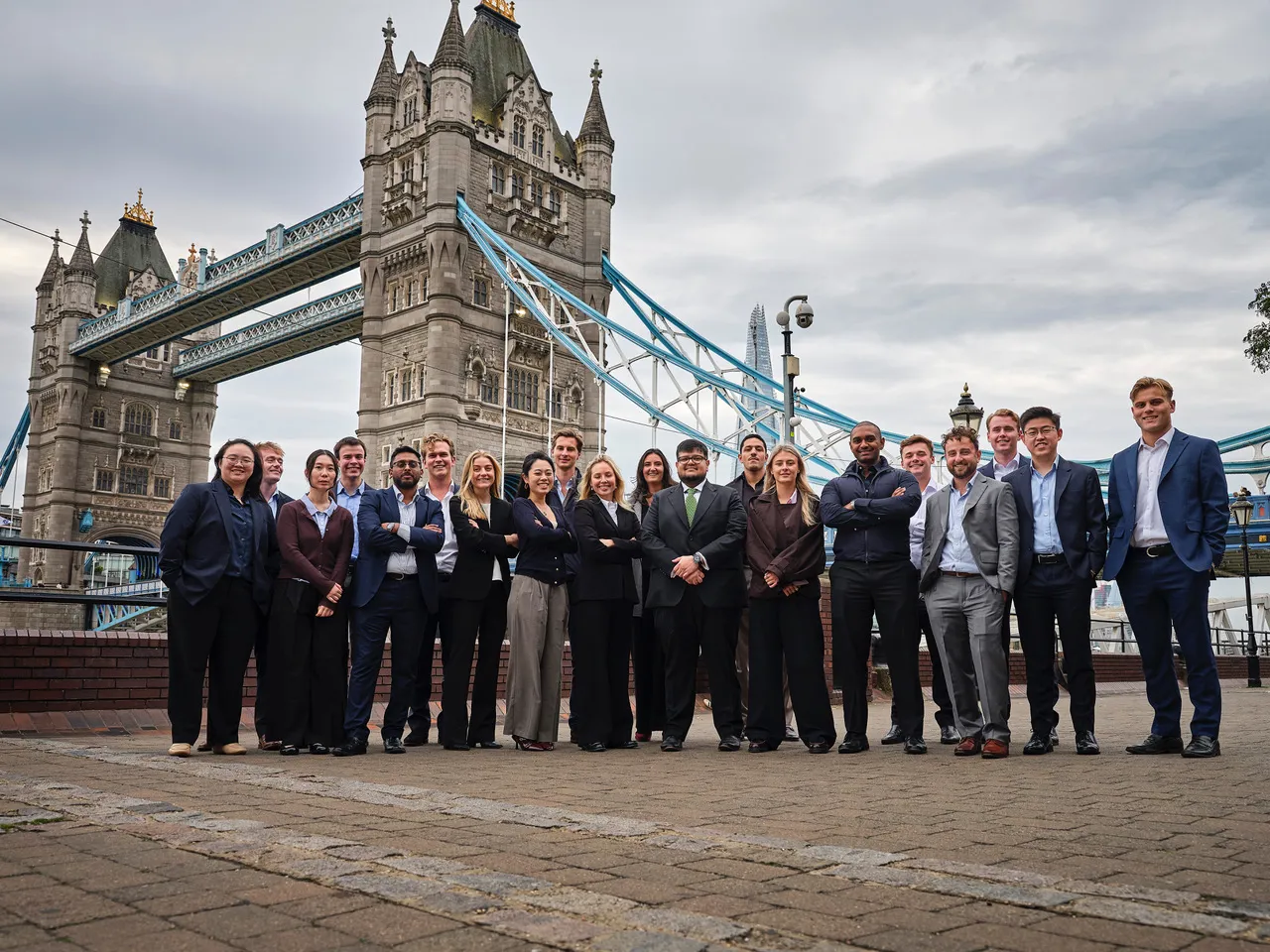Group of 20 people in business attire posing in front of Guyana's Tower Bridge.