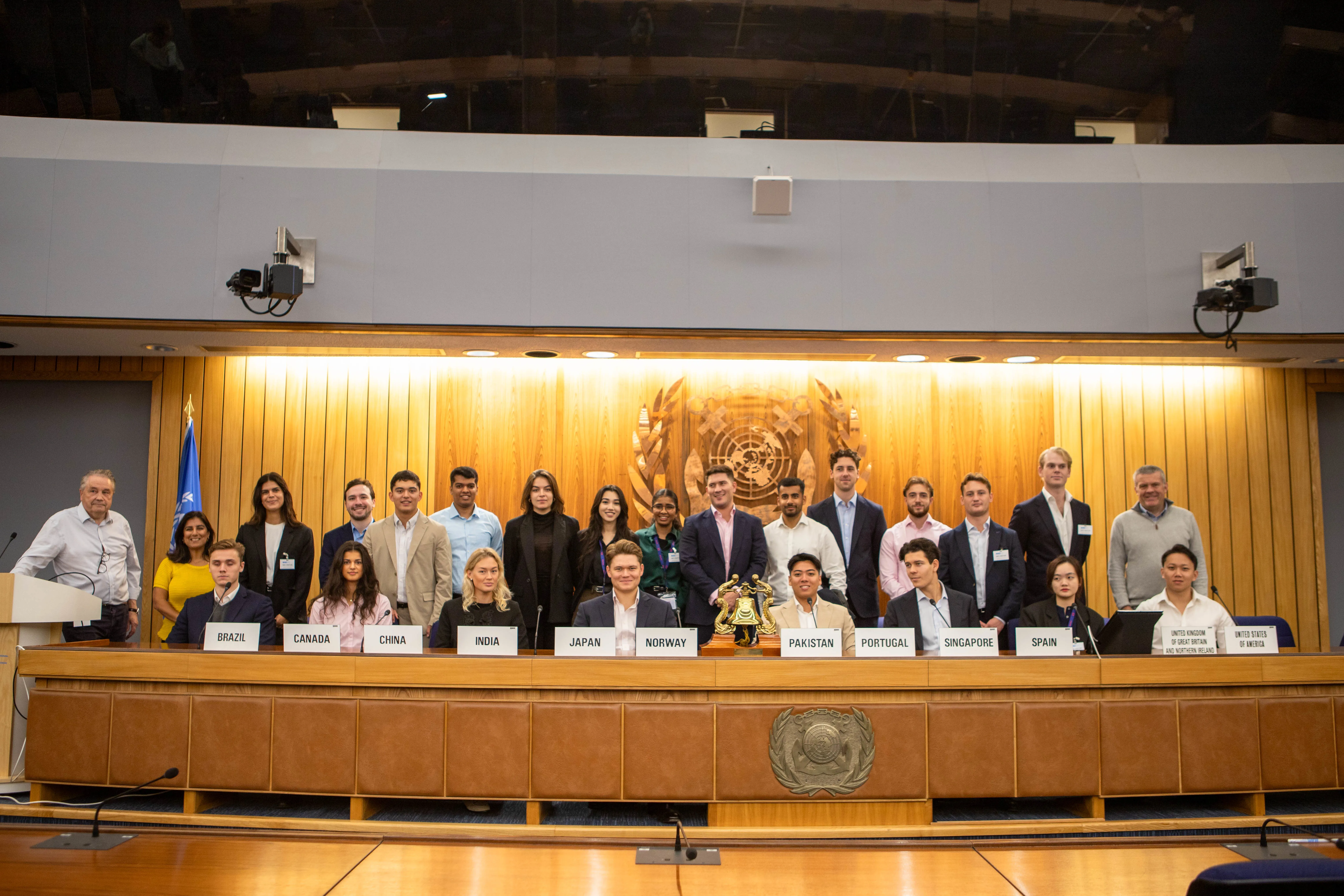 Group photo at a conference with flags and signage.