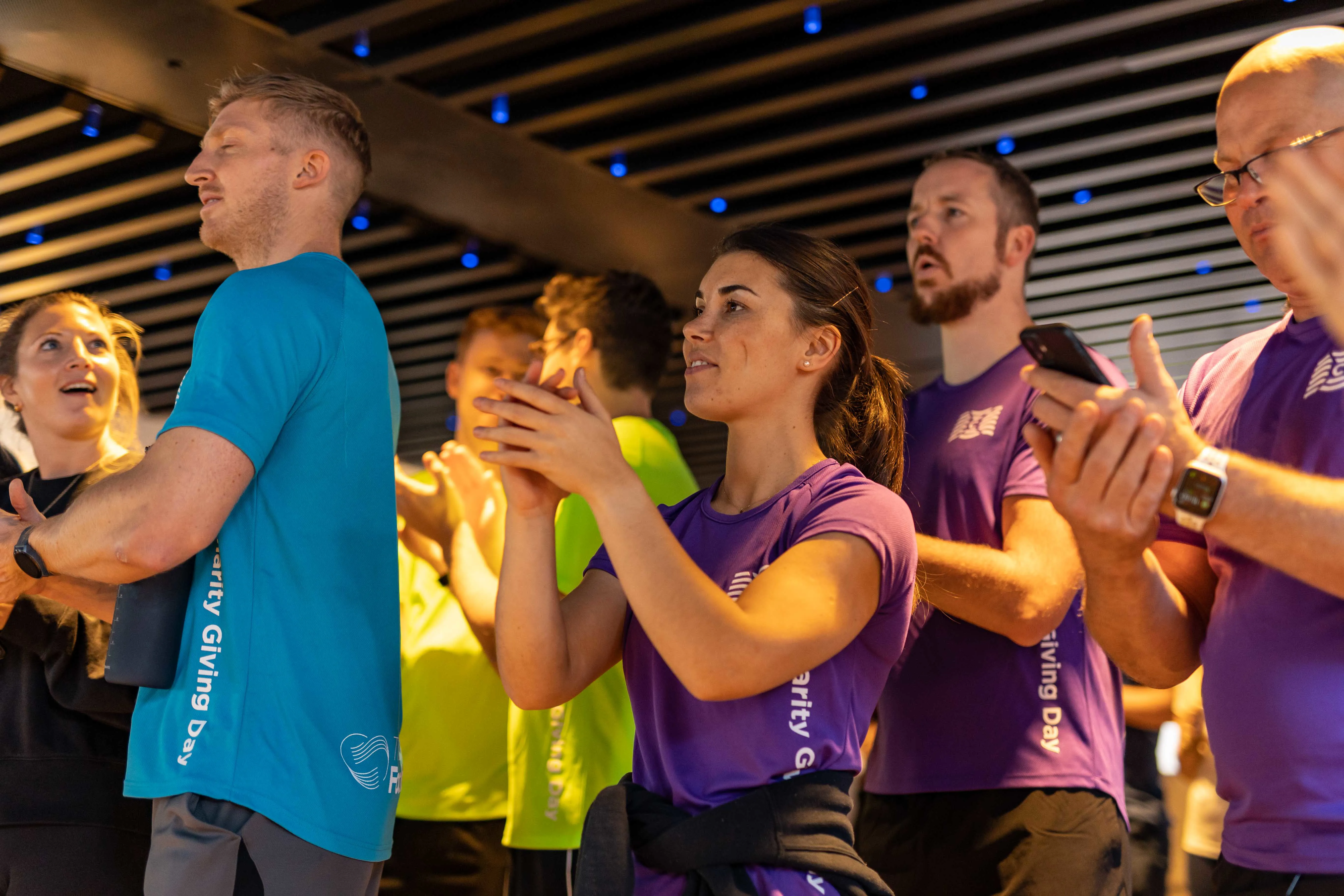 Group of people clapping and celebrating indoors.