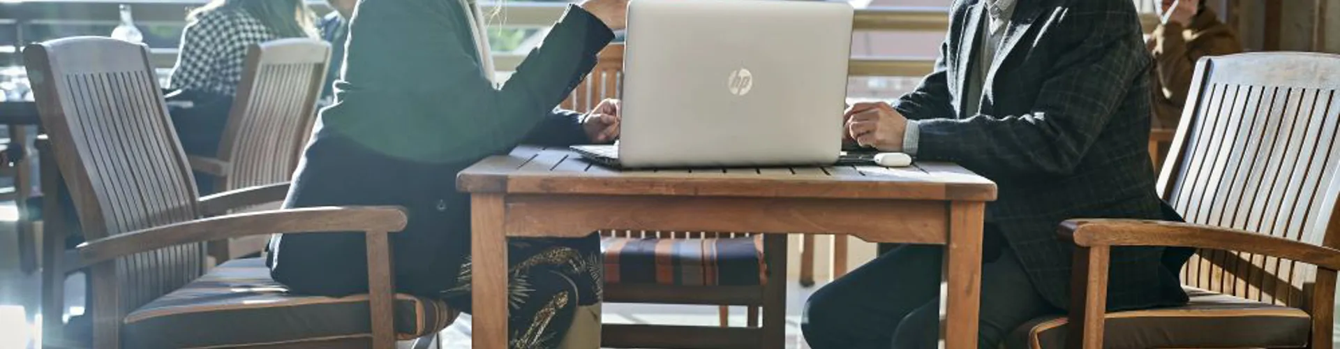 two colleagues discussing work on a laptop outside