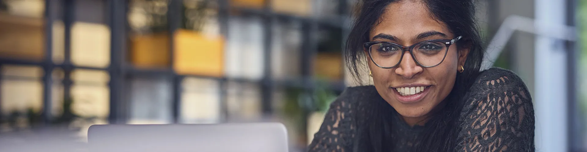 woman sitting at table with her laptop and smiling
