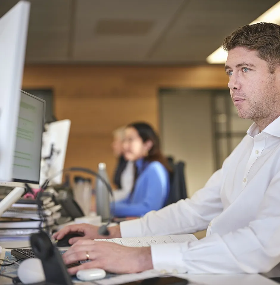 A man working at a desk with computer monitors.