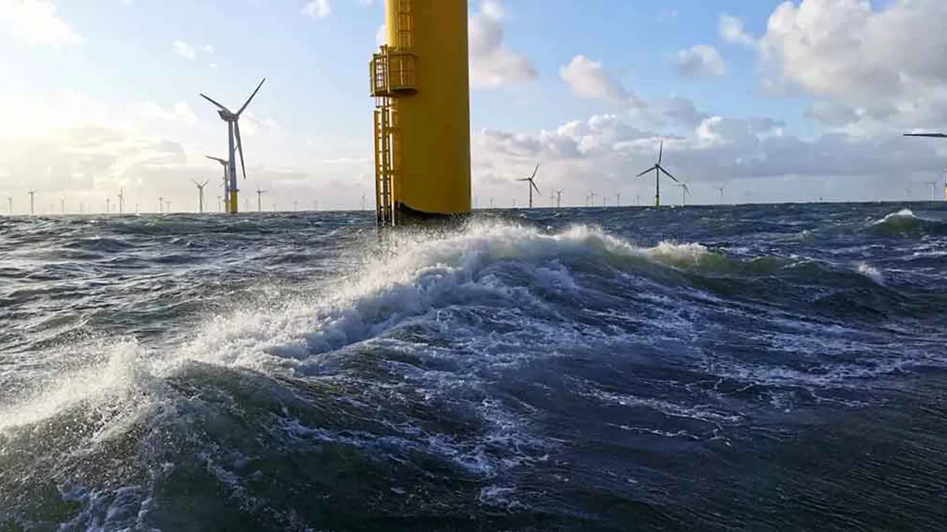 waves in the sea at bottom of a wind turbine