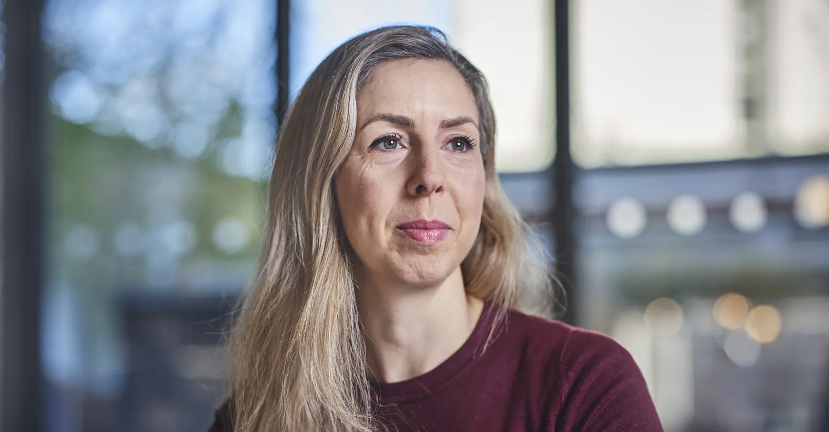 woman with blonde hair looking into distance and smiling