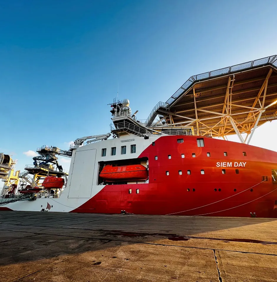 Large ship named "SIEM DAY" docked at a port.
