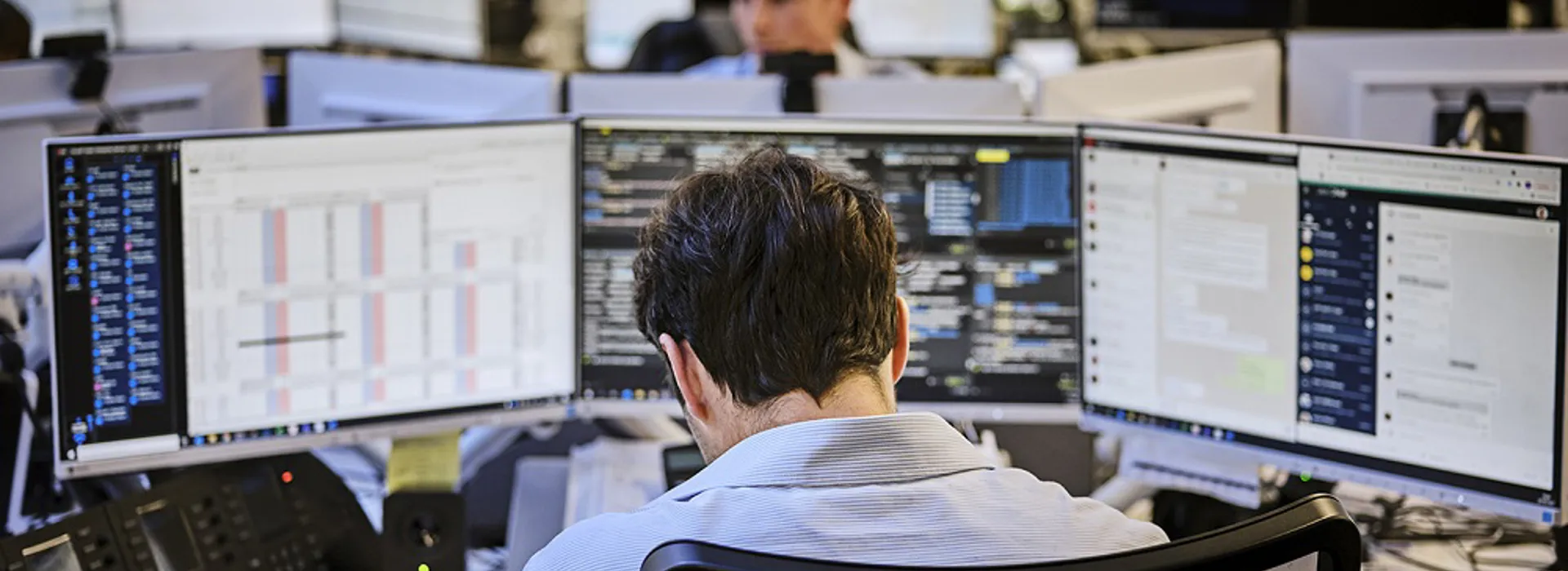 Person working at multiple computer monitors.