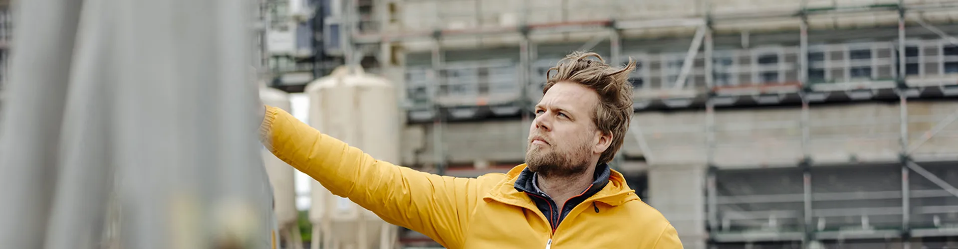Man holding laptop, construction site in the background