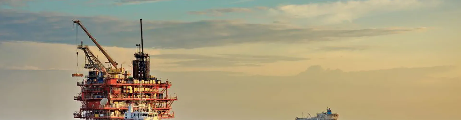 Offshore oil rig against a sunset backdrop.