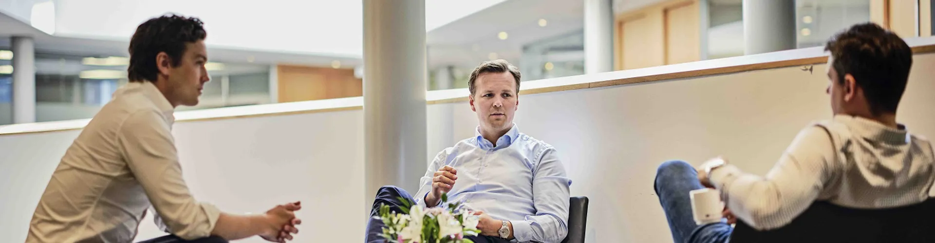 Three men seated in a modern office setting.