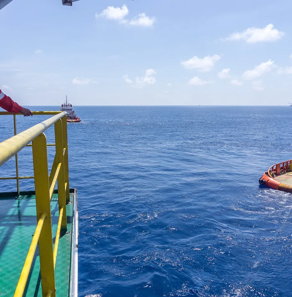 Man in uniform looking out over sea where boat is