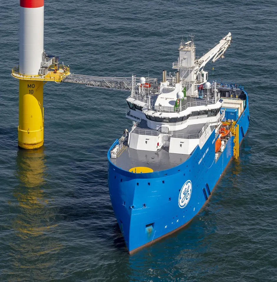 Blue support vessel near a wind turbine.