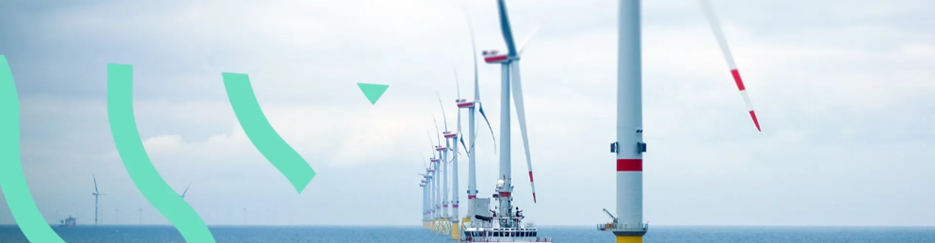 A ship next to wind turbines in the ocean.