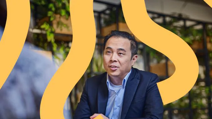 Man in a suit speaking with vibrant background.