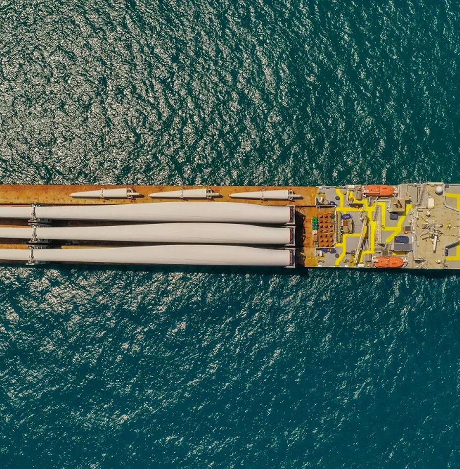 Aerial view of a ship with wind turbine blades.