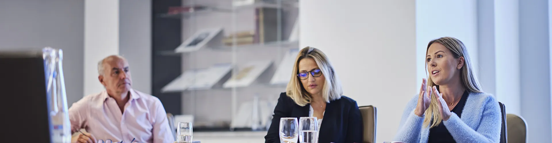 woman talking in a meeting with two other colleagues