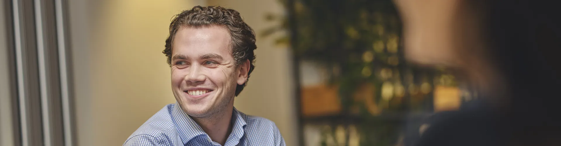 Smiling man in a meeting, laptop in foreground.