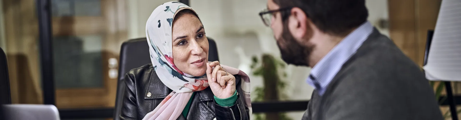 two colleagues discussing work on a laptop in a meeting room