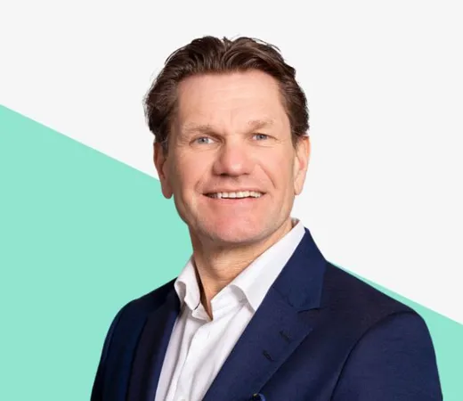 Smiling man in a suit with a light background.