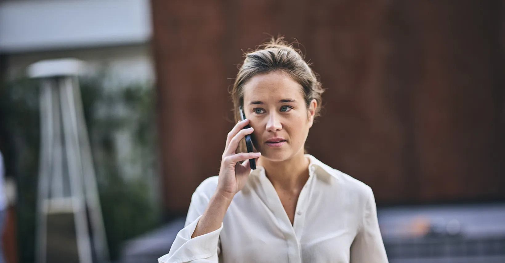 woman in white shirt on phone, outside, walking