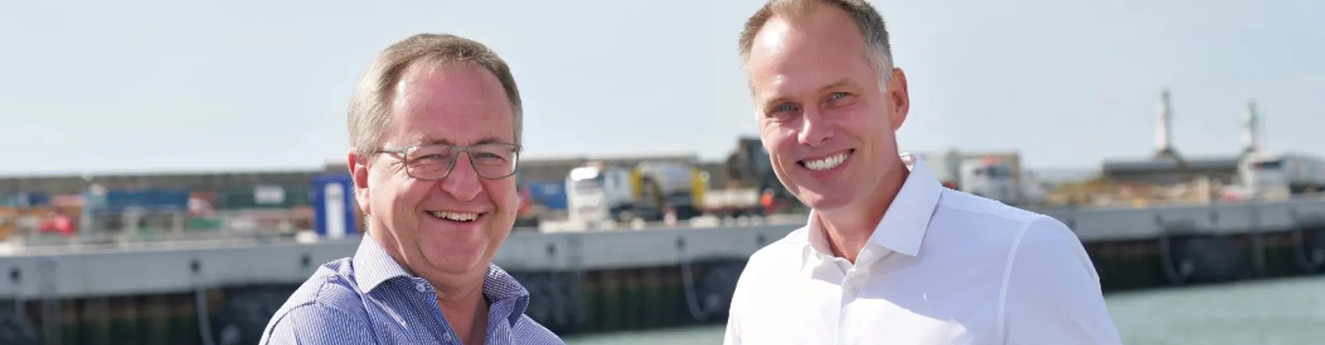Two men shaking hands by the water.