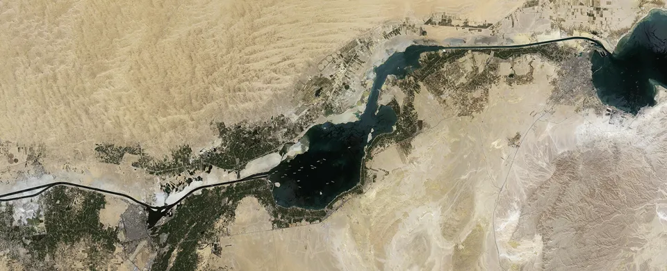 Aerial view of desert landscape intersected by a dark blue river with green agricultural land.