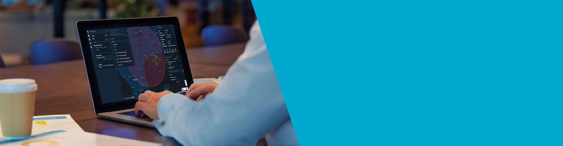 Person using a laptop on a table with a cup.