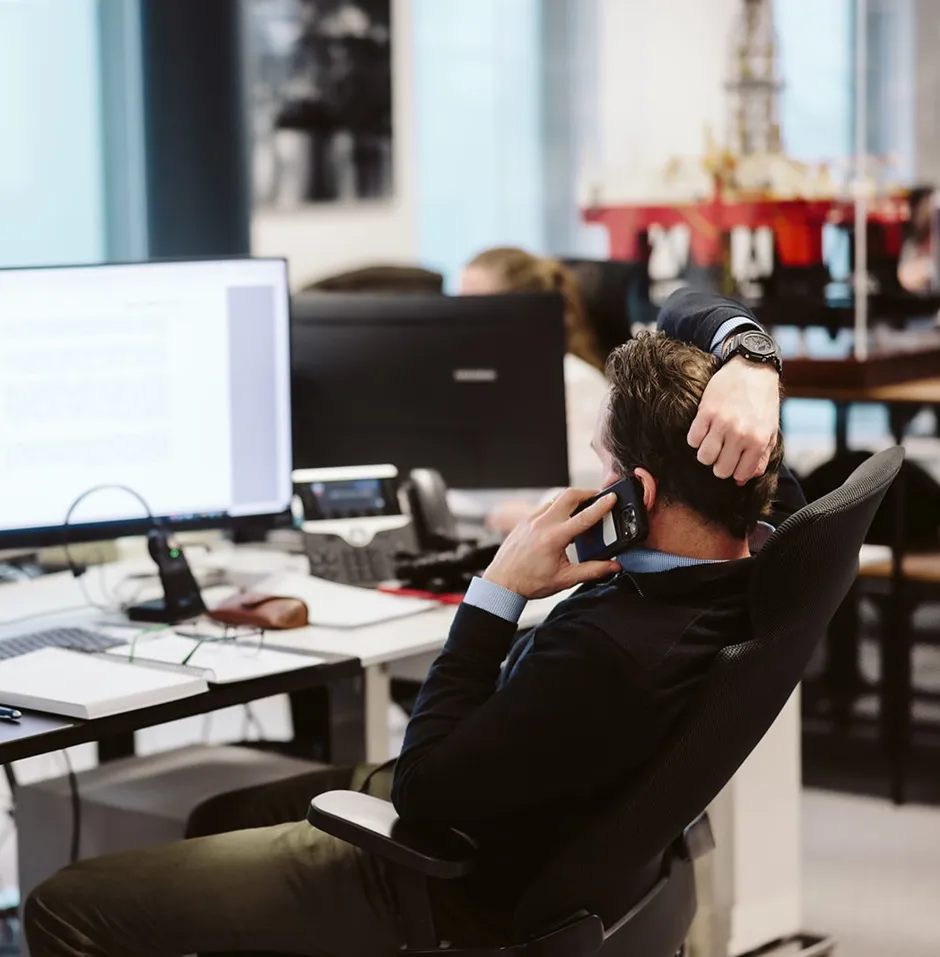 Person on phone at a dual monitor workstation.