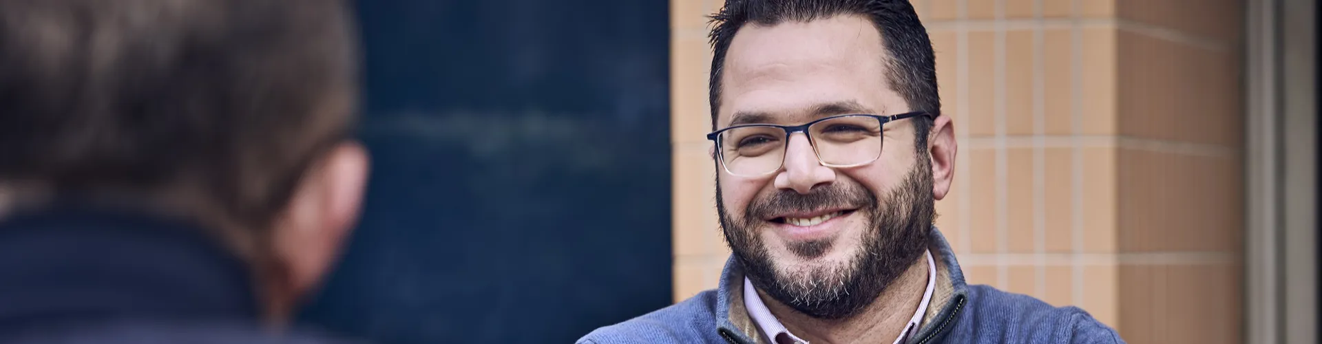 man with his arms crossed talking to colleague outside