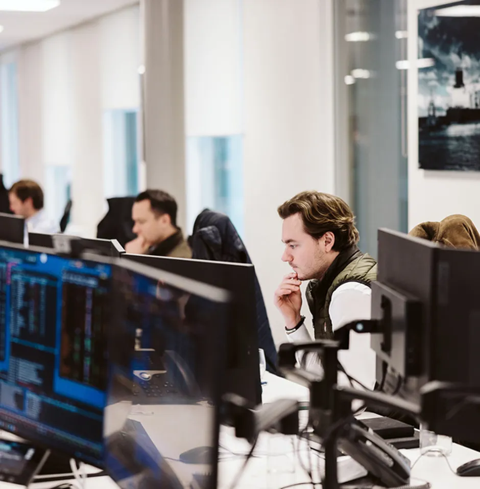 Modern office with multiple workers at desks focused on their computer screens.